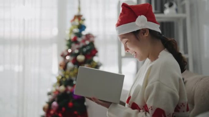 亚洲女性在圣诞节打开礼品盒