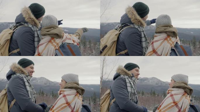 快乐的年轻夫妇的肖像，看着令人惊叹的冬季风景，在山上户外聊天