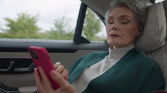 一位发型时尚，妆型完美的中年女商人正在用粉红色的手机向丈夫发短信。