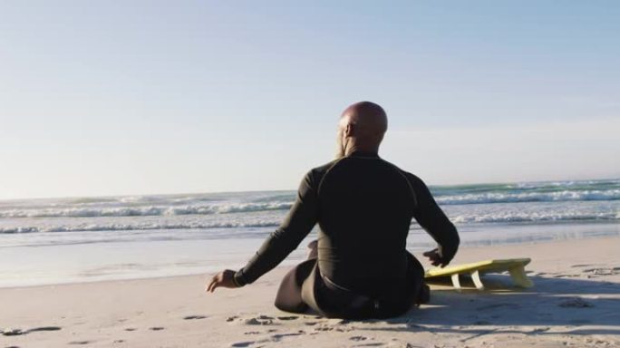 资深非裔美国男子坐在沙滩上冲浪板