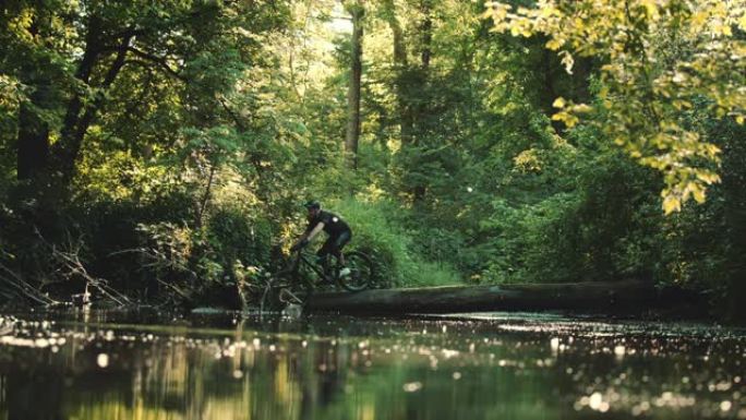 超级SLO MO MTB骑自行车的人在树干上掉入溪流