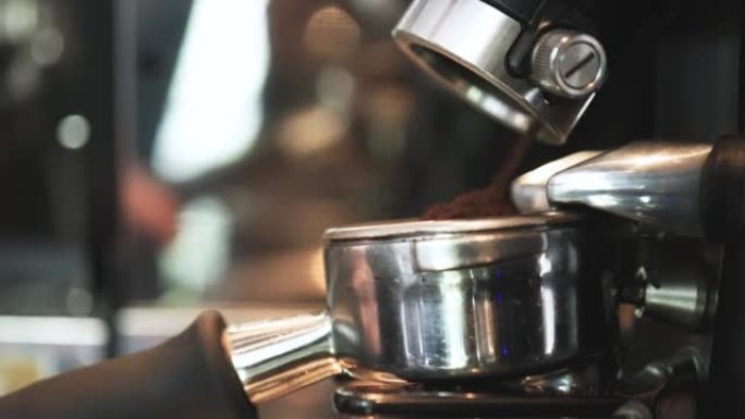 男士咖啡师与咖啡机械一起工作，以压实咖啡粉，在咖啡馆煮咖啡