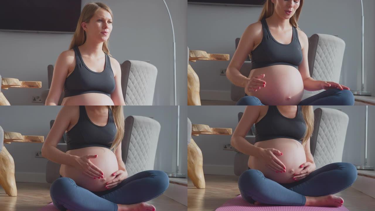 孕妇在家里的运动垫上穿着健身服呼吸和触摸胃