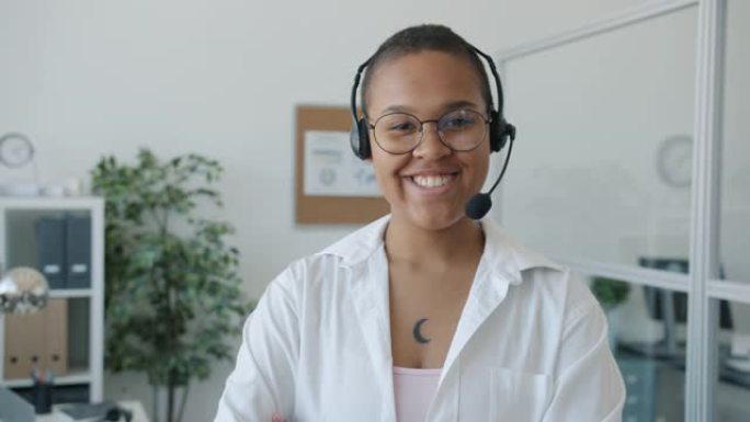 美国黑人女性呼叫中心工作人员微笑着看着办公室的相机的慢动作肖像