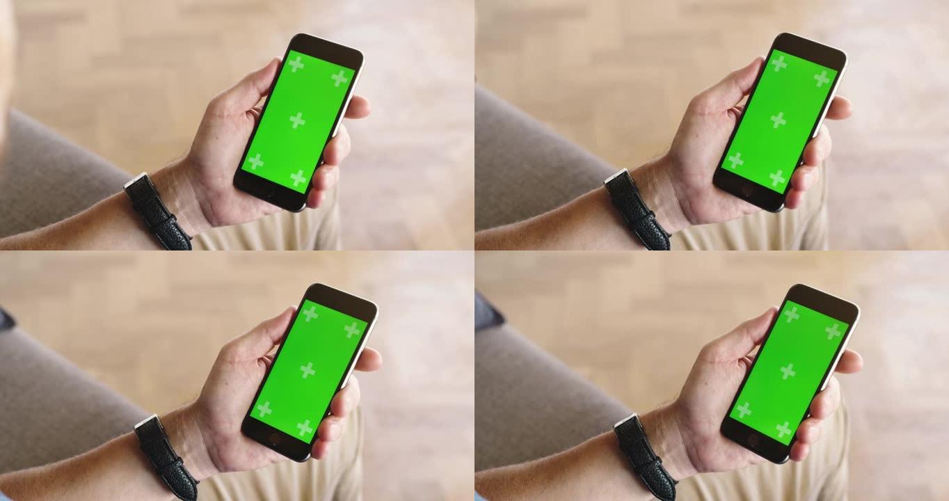 4k视频片段，一名男子坐在家里时使用带有绿屏的手机