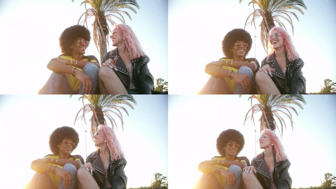 日落时两个时髦的朋友坐在海滩边聊天。