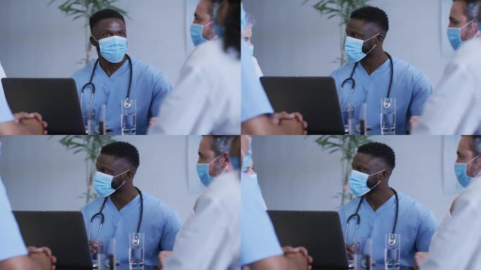 非裔美国男医生和医院同事戴着口罩在会议上交谈