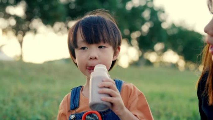 饥饿的男孩在家庭野餐时喝牛奶。
