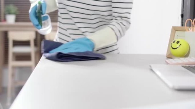 一名妇女用抗菌消毒擦拭巾清洁办公桌，以杀灭冠状病毒