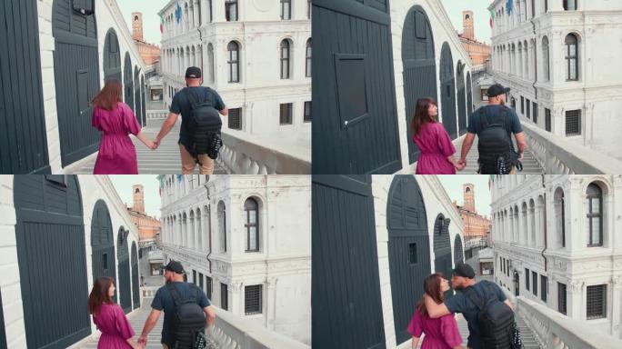 镜头跟随快乐的年轻高加索旅游夫妇走在威尼斯桥上，亲吻享受暑假。