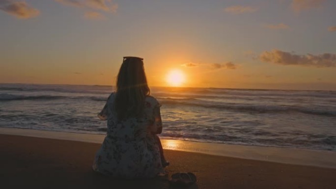 一个金发女孩坐在沙滩上的慢动作视图，撒丁岛。