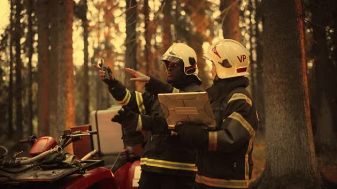 站在ATV旁边的两名专业消防员的肖像，在野火中讨论情况: 女警司与非裔美国人班长交谈，使用笔记本电脑
