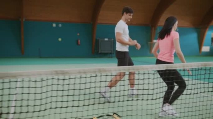年轻女子在室内网球场男教练的指导下练习跳绳