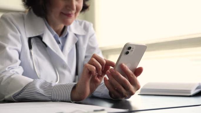 年长的女医生拿着智能手机打字给病人