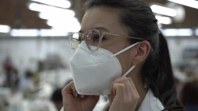 年轻女子在纺织厂调整防护口罩