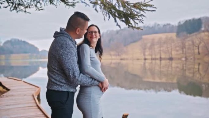 中年男子在看着河时亲吻他怀孕的妻子