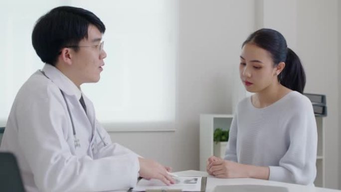 亚洲友好医生在医院办公室讨论建议病人。