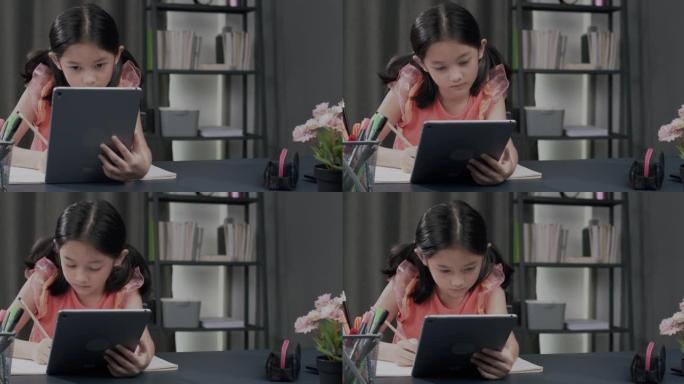 女孩在家在数字平板电脑上学习和检查作业