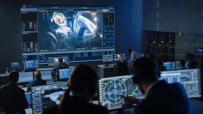 任务控制中心的一群人在大屏幕上与空间站上的宇航员建立了成功的视频连接。飞行控制科学家坐在前面的电脑显