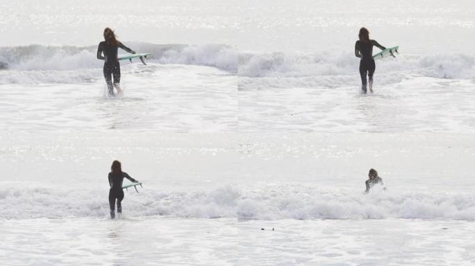 混血女子带着冲浪板跑进海里的后视图