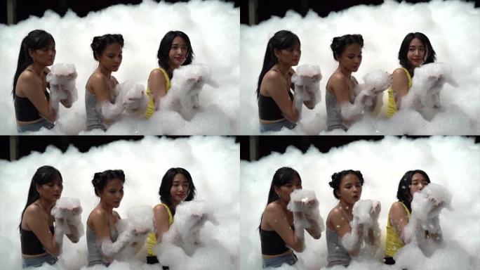 4k慢动作视频镜头三个亚洲青少年在假期玩一个有趣的泡沫派对。泰国曼谷