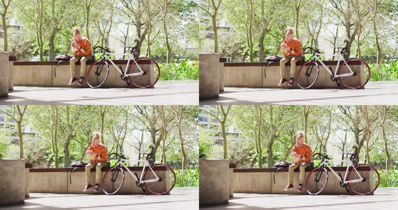 白化病非裔美国男子，长发lock坐在公园里，骑自行车吃三明治