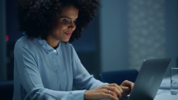 深夜在大城市办公室工作的成功的非裔美国女商人在笔记本电脑上工作。分析财务报告、市场研究和计划的女执行