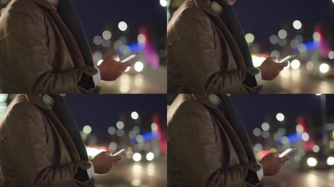 SLO MO无法识别的男人晚上在城市使用智能手机