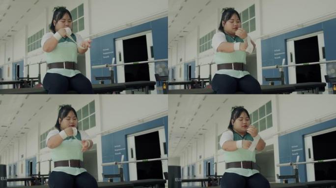 坐轮椅的亚洲女运动员在健身房锻炼前做好准备。
