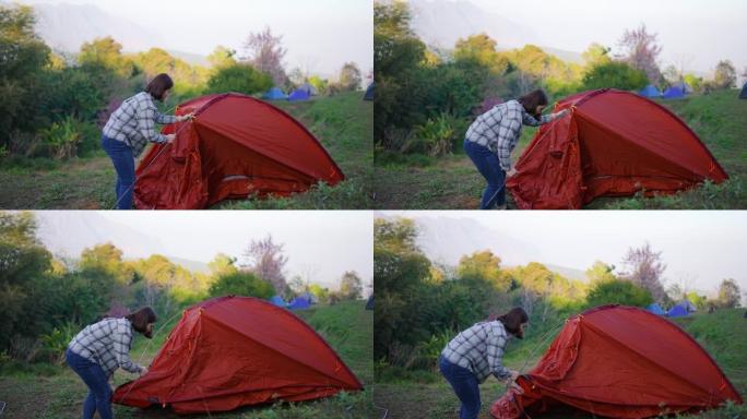 女旅行者在山上的露营地搭建帐篷