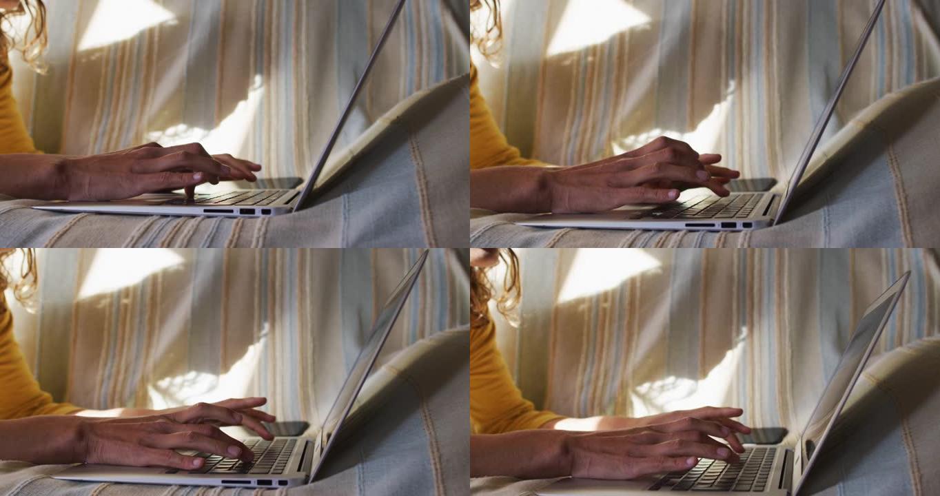 在阳光明媚的客厅里，用笔记本电脑躺在沙发上的混血女人的手