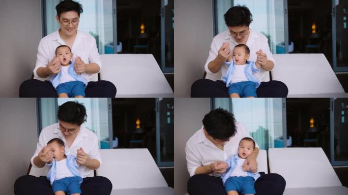 父亲坐着和可爱的新生男婴玩耍。单身父母，真正的生活方式育儿父亲时刻亲吻和抱着儿子。