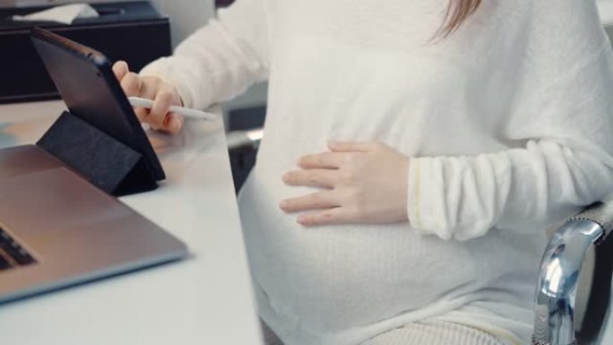 怀孕在家在数字平板电脑上远程工作。