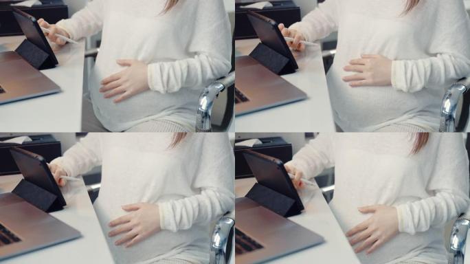 怀孕在家在数字平板电脑上远程工作。
