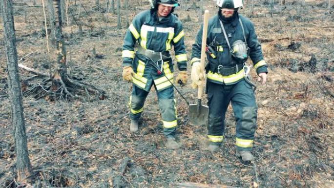 两名穿着安全服装的消防员正穿过森林火区