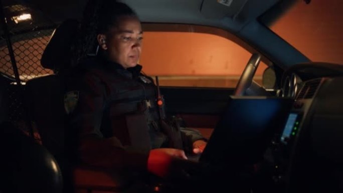 在交巡警巡逻车内:黑人女执勤警官使用笔记本电脑检查犯罪嫌疑人的背景，车牌，执照和登记。打击罪行处处长