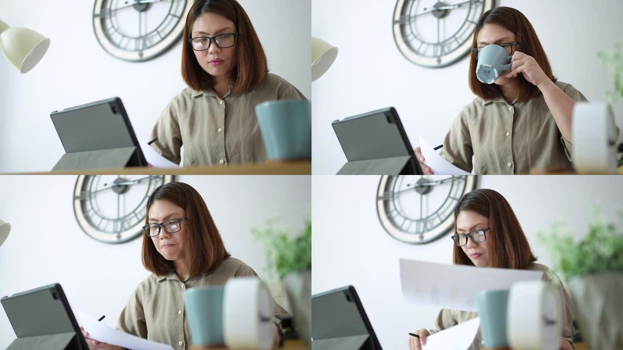 女人在家工作，分析图形和使用数字平板电脑