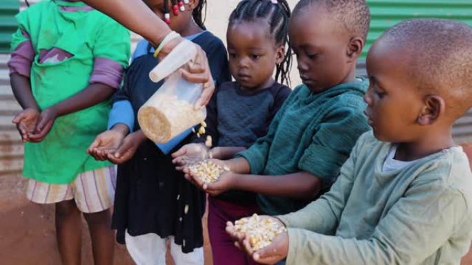 非洲的贫困。一小群饥饿的非洲黑人儿童在慈善组织分发玉米时伸出双手