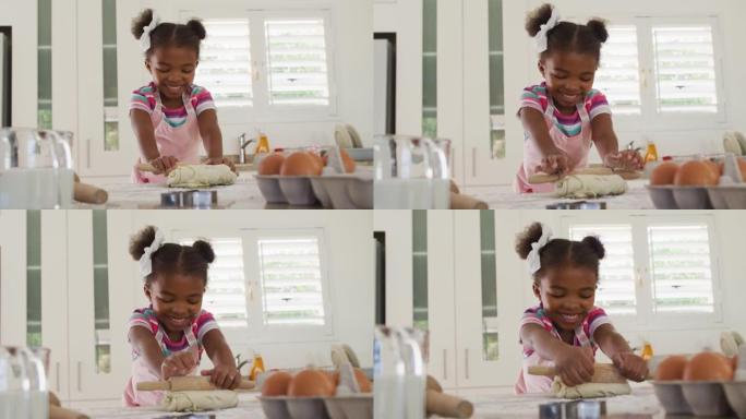 快乐的非洲裔美国女孩在厨房里滚动面团