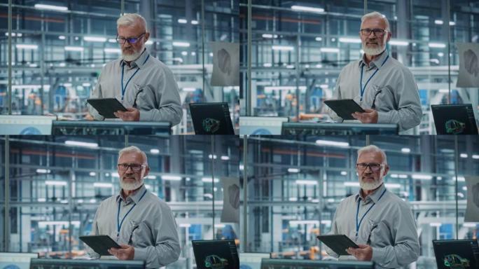 汽车厂办公室: 男总工程师的肖像用平板电脑看着相机，微笑着。自动化机器人手臂装配线制造高科技电子设备