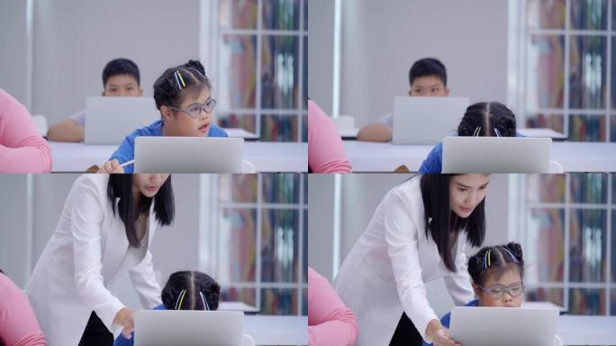 10岁的亚洲唐氏综合症女孩在小学课堂上举手，而年轻的女老师在教室里教计算机。残疾收集2019