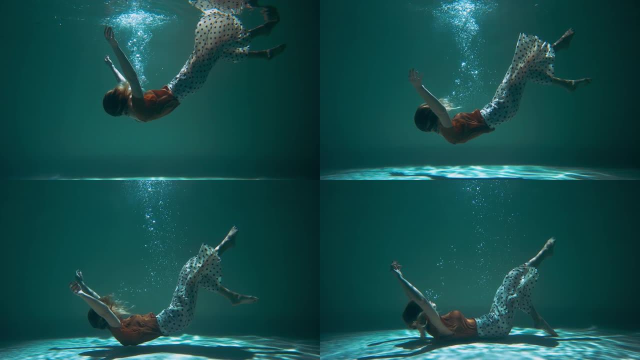 情感抑郁的电影概念。无助的年轻美女沉入浅蓝色水中慢动作。