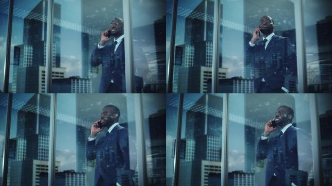 成功的非洲裔美国商人站在办公室，打电话完成交易，看着窗外的肖像。成功的股票市场投资者做电子商务。外射