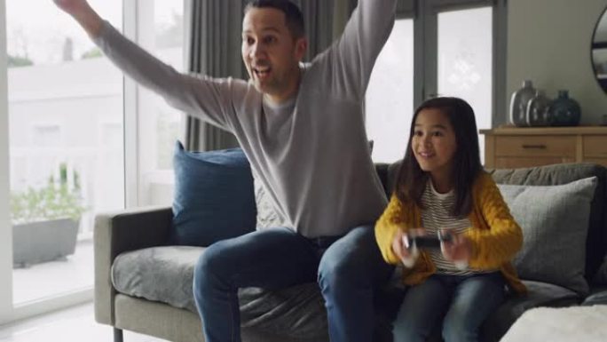 一个父亲和女儿在家里的沙发上玩电子游戏的4k视频片段
