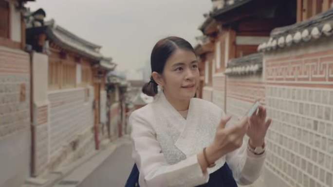 年轻的亚洲女性在韩国旅行时使用智能手机拍照。