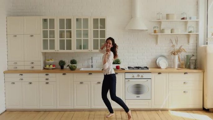 在现代宽敞的厨房里，活泼的家庭主妇赤脚唱歌跳舞
