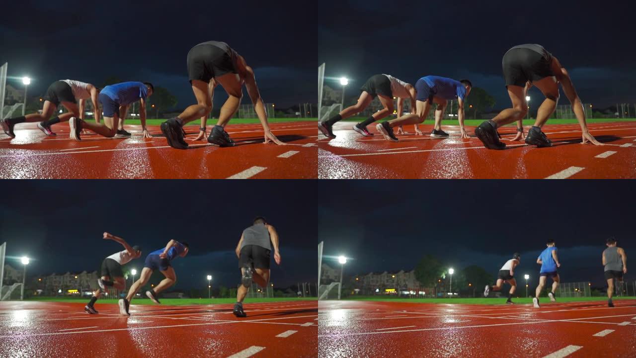 慢动作后视亚洲中国男运动员在体育场下雨的傍晚开始在男子跑道上跑步