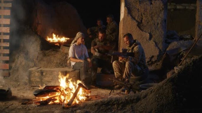 士兵和青少年在篝火旁休息