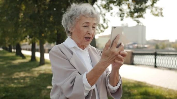 开朗的高级女子在城市街道户外聊天聊天在线视频通话