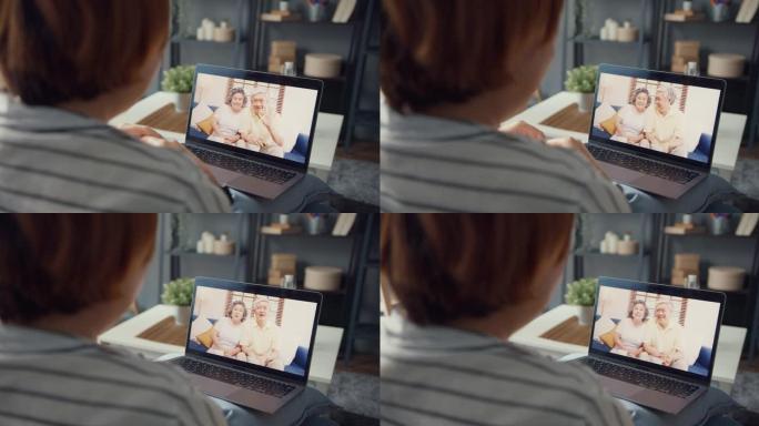 年轻的亚洲女孩使用笔记本电脑视频通话会议与年迈的家庭爸爸和妈妈聊天，在家工作时坐在客厅的沙发上。
